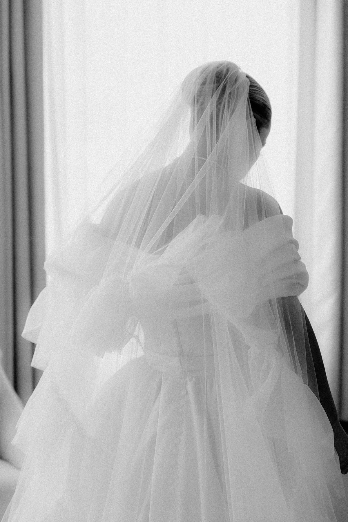 Bride photographed from behind wearing full tulle gown and veil in Brisbane House Hotel suite before ceremony