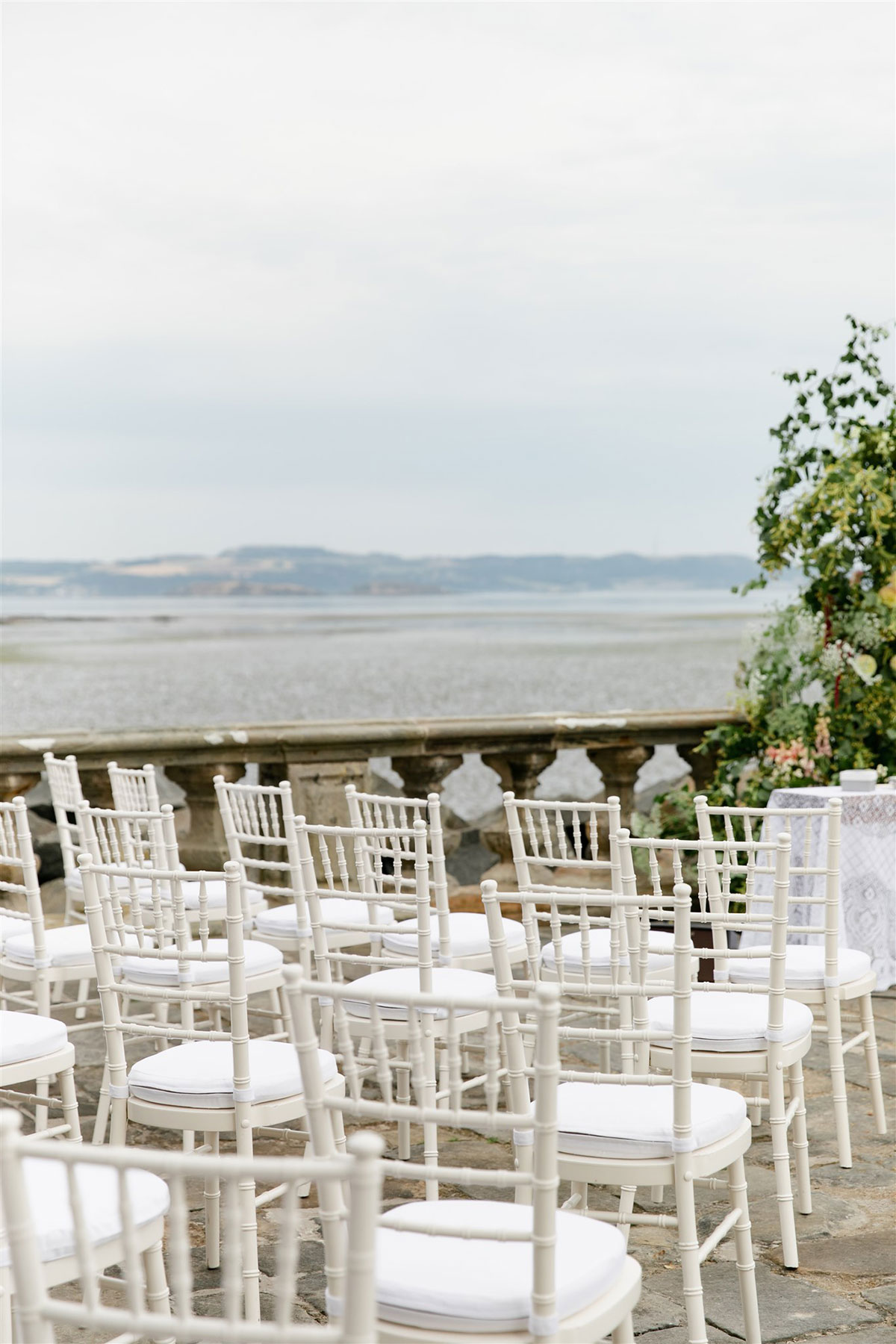 Barnbougle Castle seaside coastal wedding venue with rows of white chiavari chairs set for outdoor wedding ceremony on terrace 