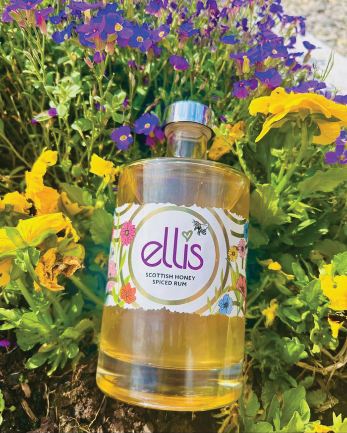 A bottle of Ellis Honey Spiced Rum pictured on colourful flowers and grass