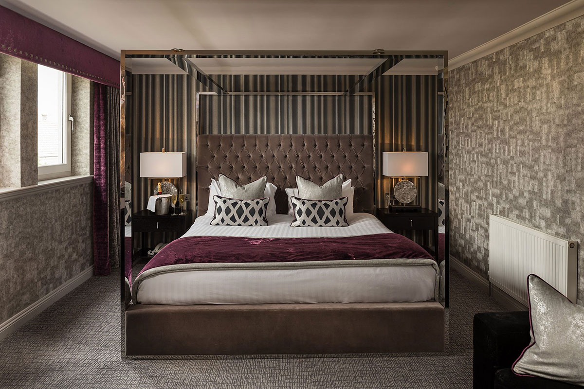 The Carlton Hotel honeymoon suite featuring a four-poster bed, patterned wallpaper and soft furnishings.