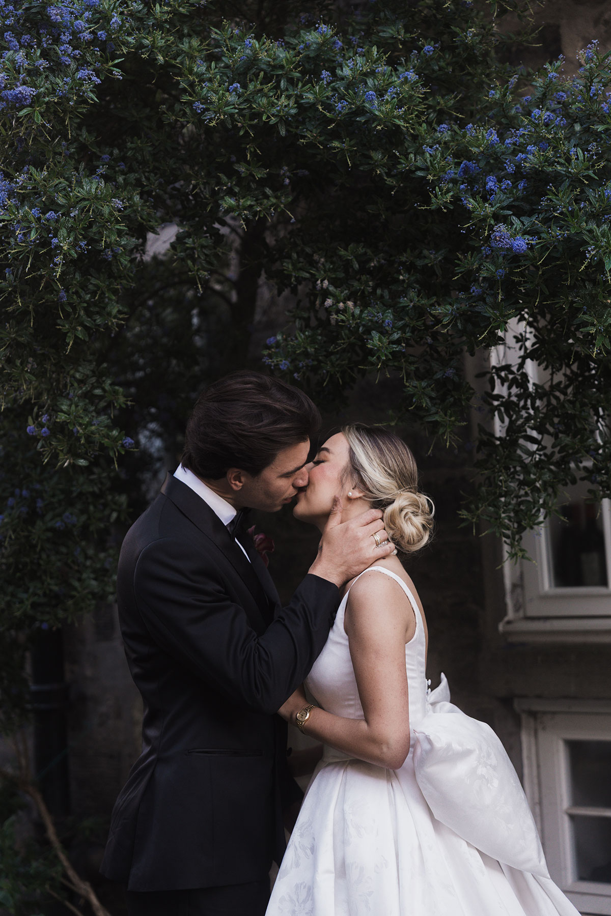 Close-up of bride and groom kissing under a flowering bush during Mansfield Traquair wedding portrait session