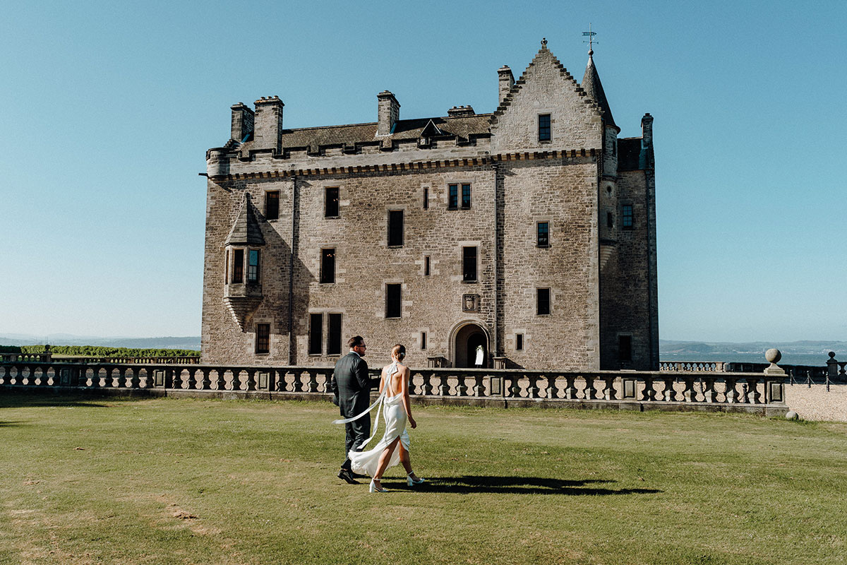 Wedding couple walking together outside Barnbougle Castle, part of Rosebery Estates near Edinburgh