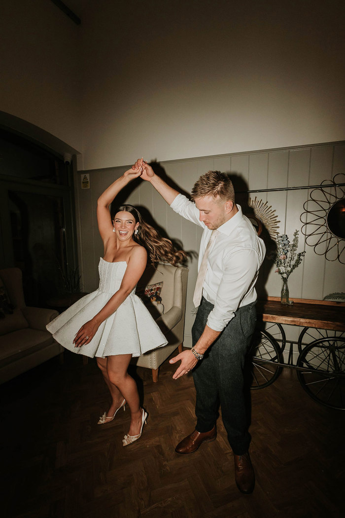 a groom spinning a bride wearing a short white dress during a wedding reception at Dunglass Estate