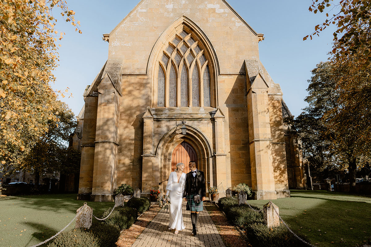 Bride and groom walking outside Dornoch Cathedral after their wedding ceremony in Scotland