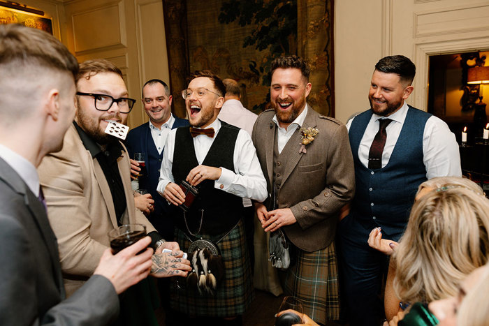 a group of people laughing and looking surprised as a magician performs a card trick