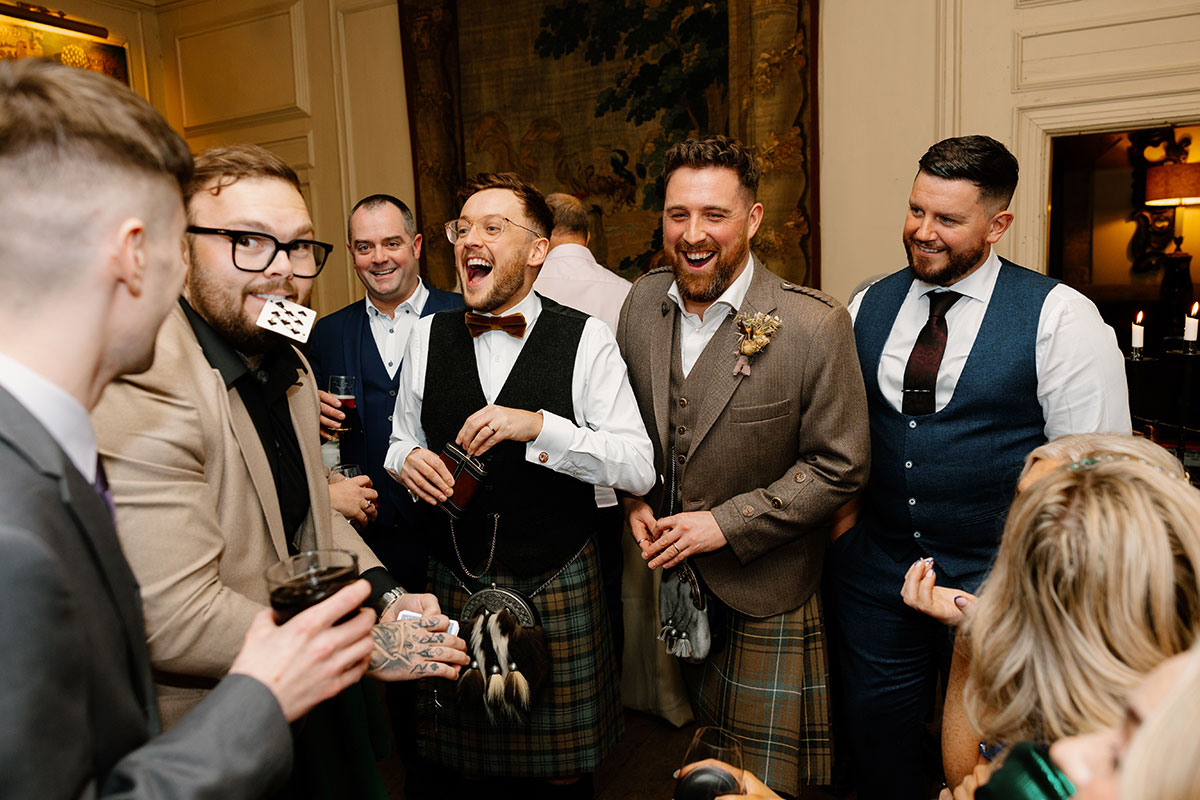 a group of people laughing and looking surprised as a magician performs a card trick