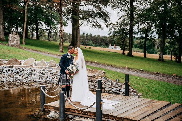 Bride and groom stand on deck over water