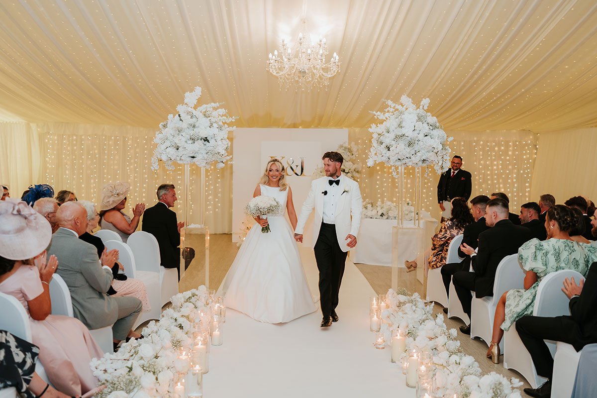 Bride and groom walking back up aisle as guests applaud at Ingliston Country Club ceremony