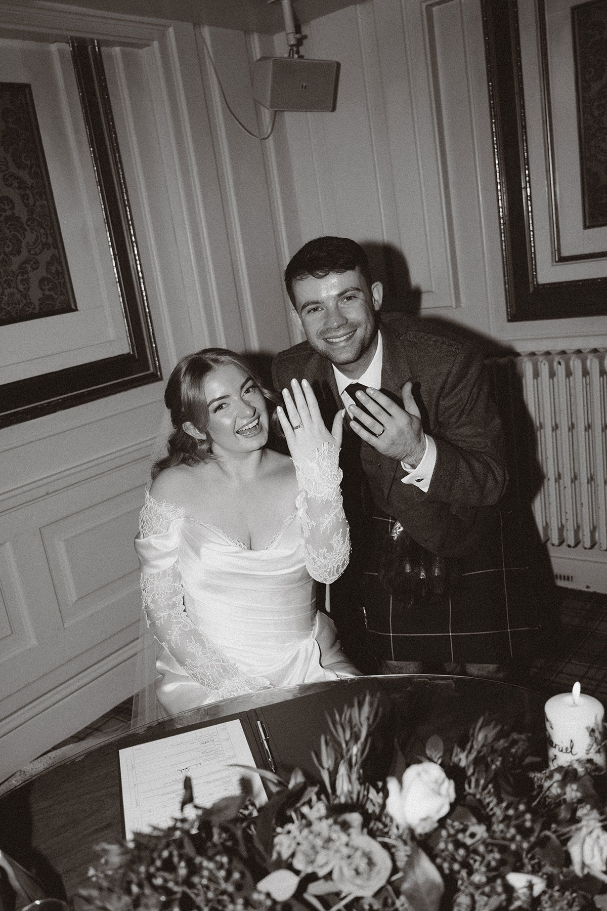 Newlywed couple signing wedding register and showing rings during Scottish ceremony moment