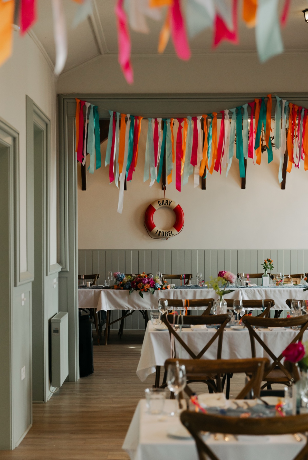Nautical wedding reception styling with colourful hanging ribbons and floral arrangements at The Dougarie Boathouse on Arran.