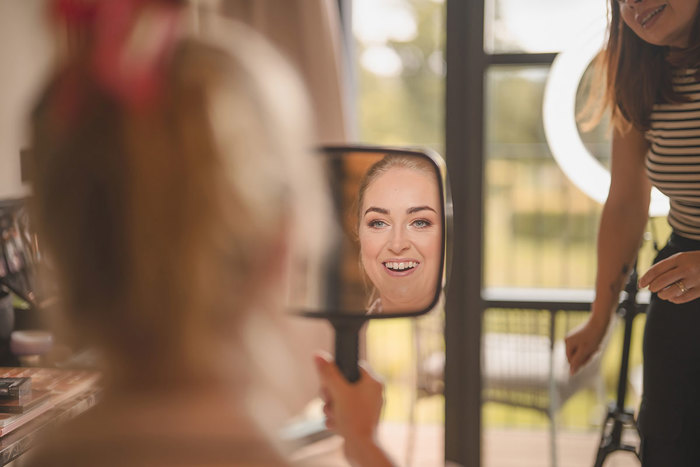 A woman looks at her reflection in a hand held mirror