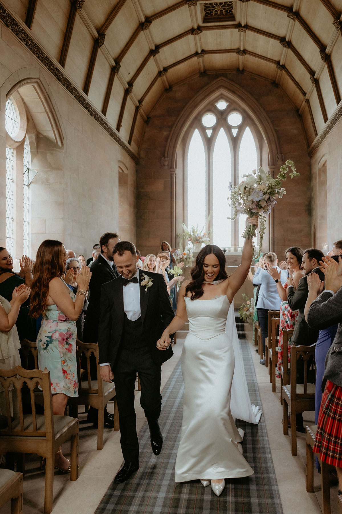 Bride and groom walking down chapel aisle after ceremony at Rosebery House and Steading, Midlothian wedding venue.