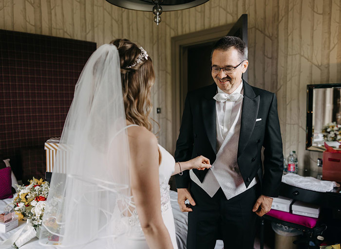 A first look between a bride and her father with with the bride adjusting her father's suit jacket