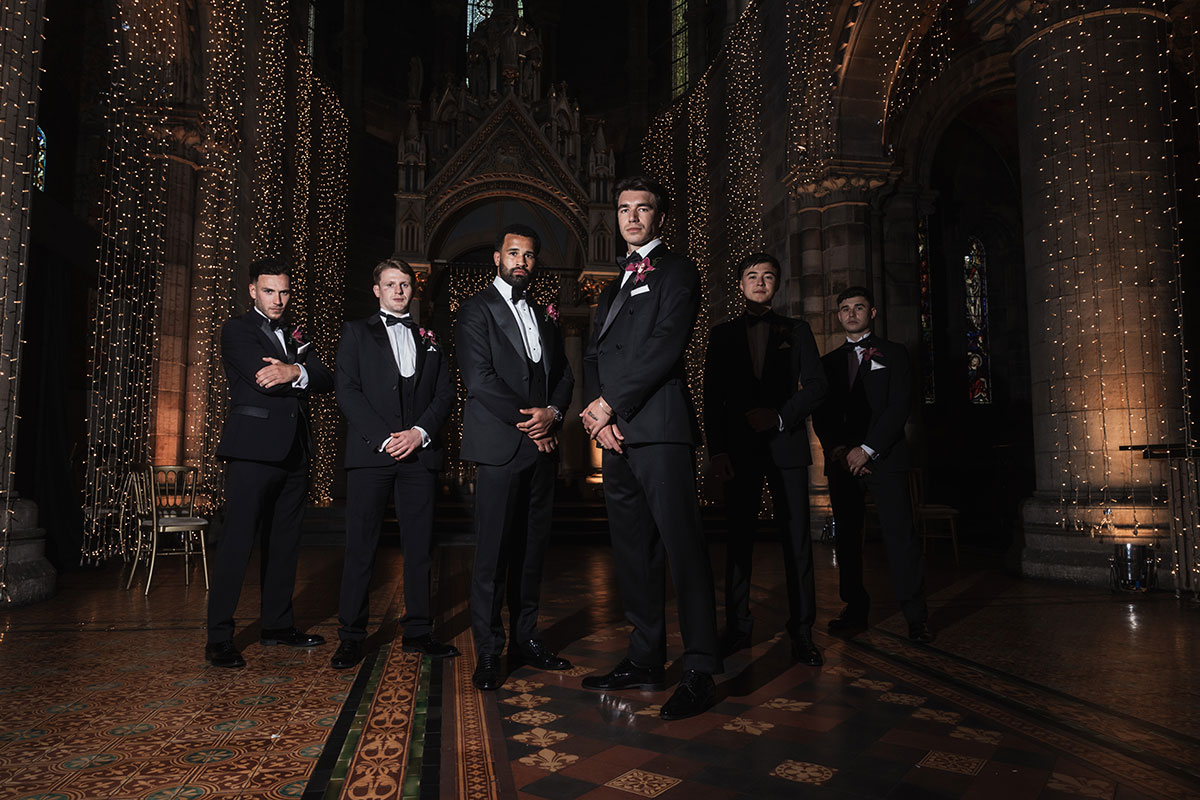 Groom and groomsmen in black tie posing inside Mansfield Traquair with dramatic lighting and ornate architecture
