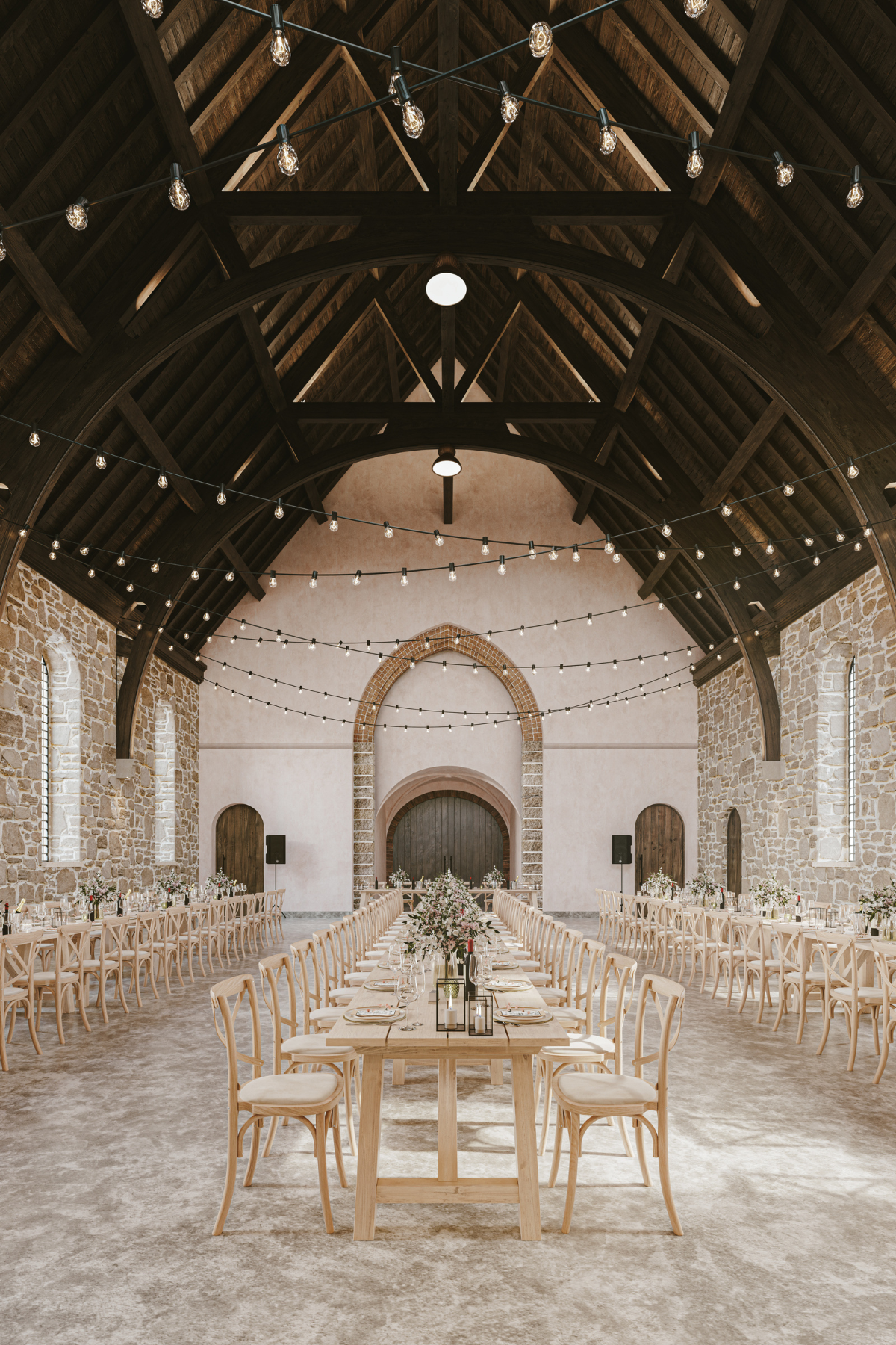 Grand Hall at The West Works Glasgow set for a wedding reception with long dining tables, stone walls and festoon lighting