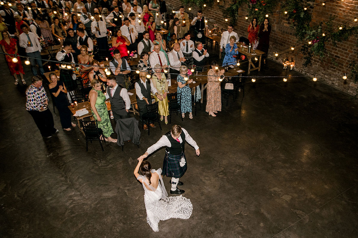 Overhead view of bride and groom sharing their first dance surrounded by guests
