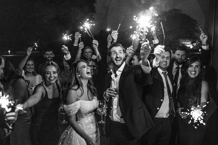 a bride and groom surrounded by people holding sparklers