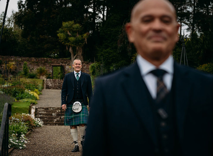 a groom wearing a kilt walks towards another who has his back turned