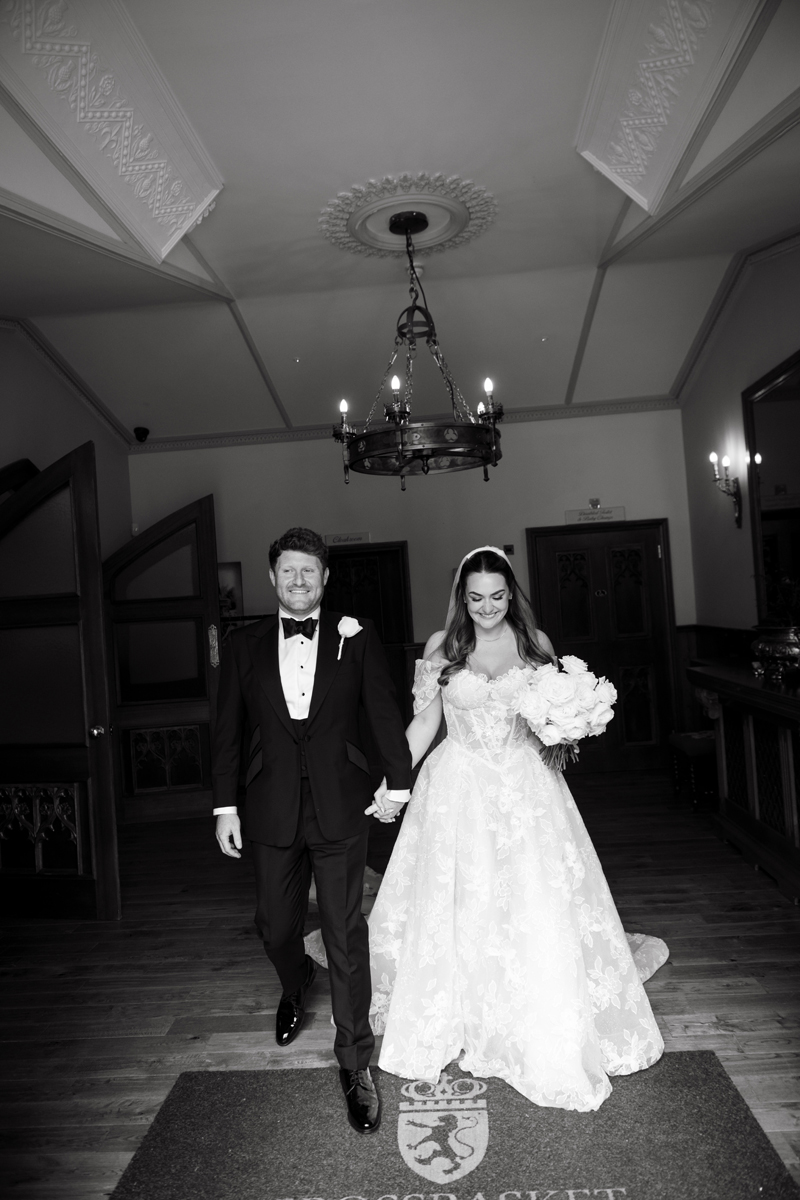 Newly married couple walking hand in hand through Crossbasket Castle after their wedding ceremony.