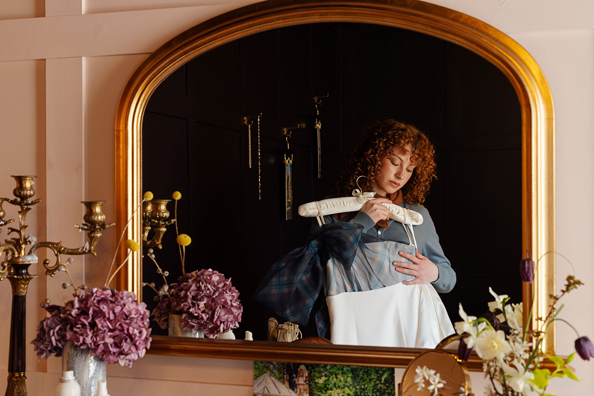 Bride holding wedding dress in mirror at The Tower Portobello