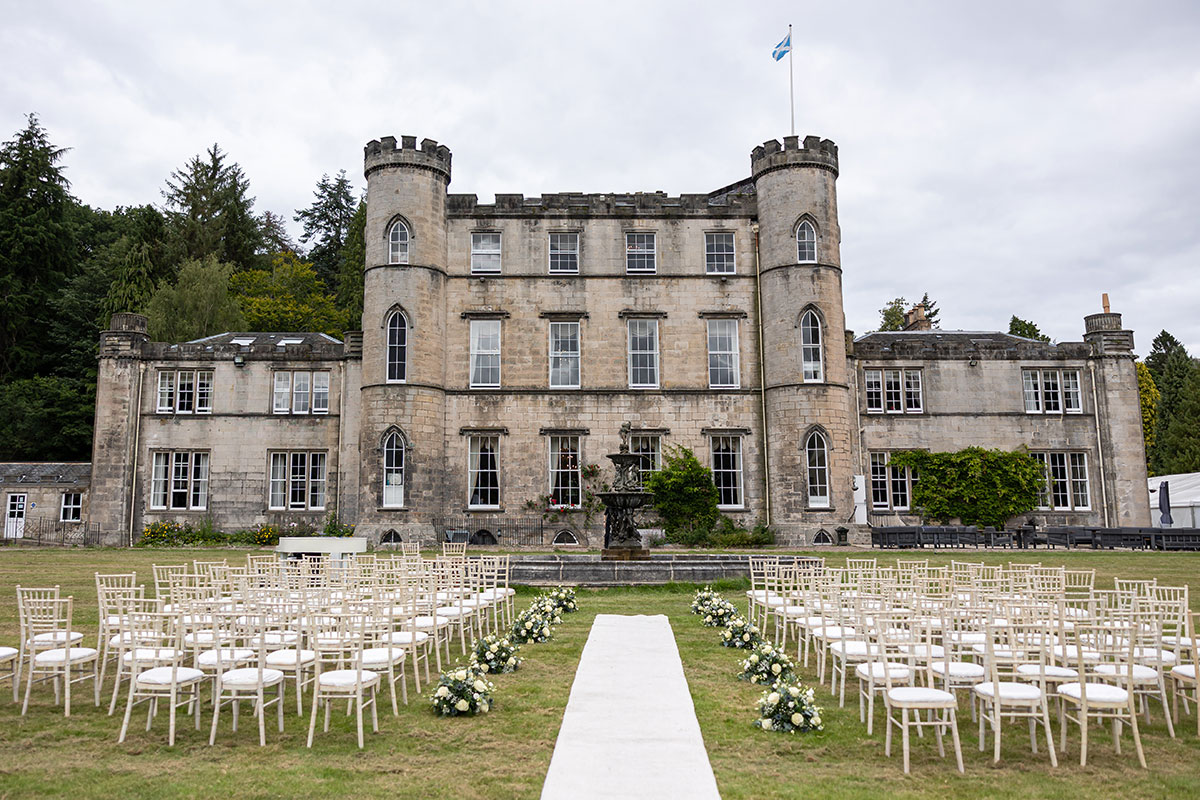 Outdoor wedding ceremony setup on the lawns at Melville Castle, with rows of chairs and floral displays positioned in front of the historic castle façade