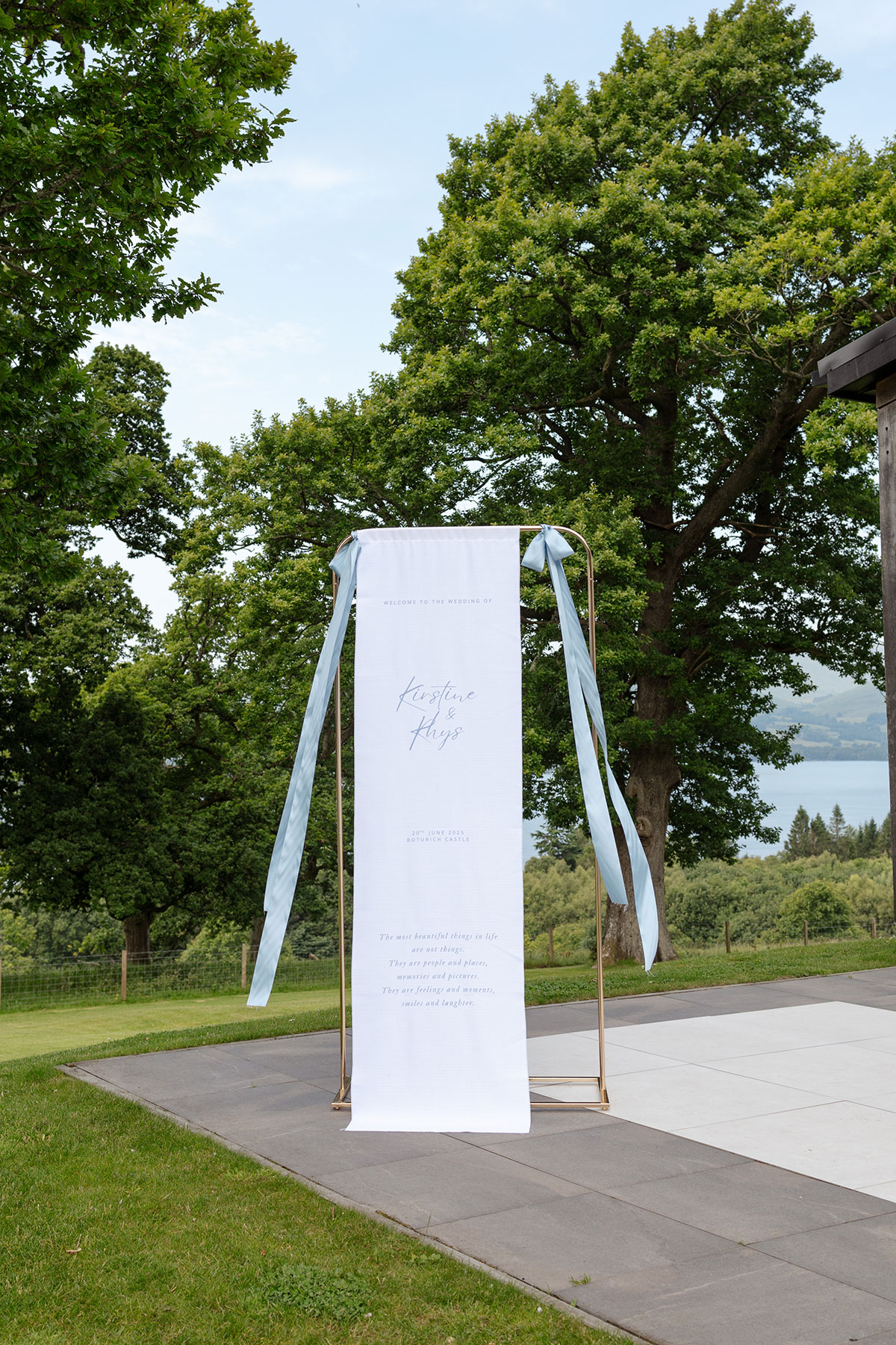 Modern wedding welcome sign displayed outside Boturich Castle overlooking Loch Lomond before the outdoor ceremony.