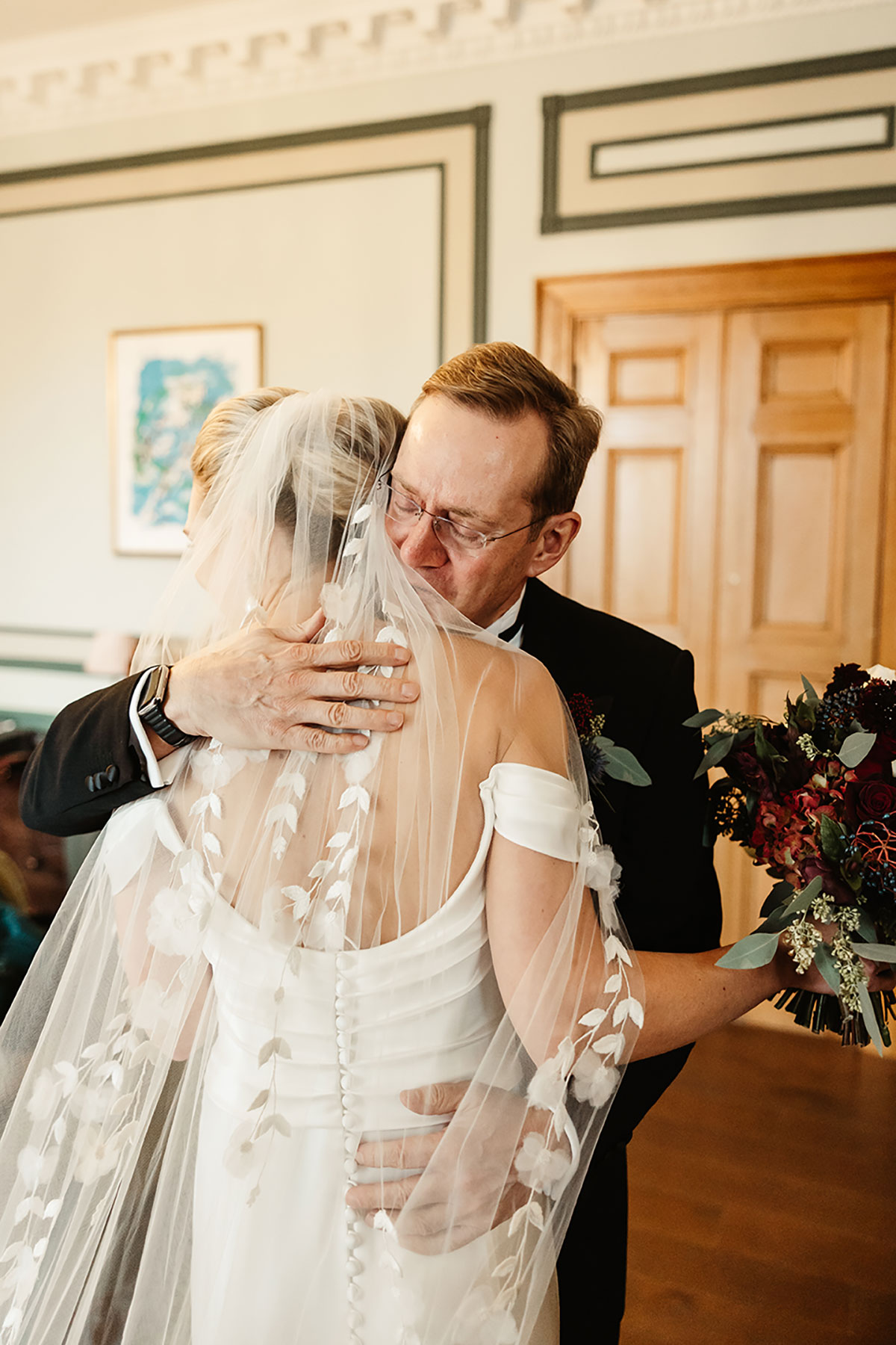 Bride hugging her father, her veil draped over his shoulder as he embraces her tightly.