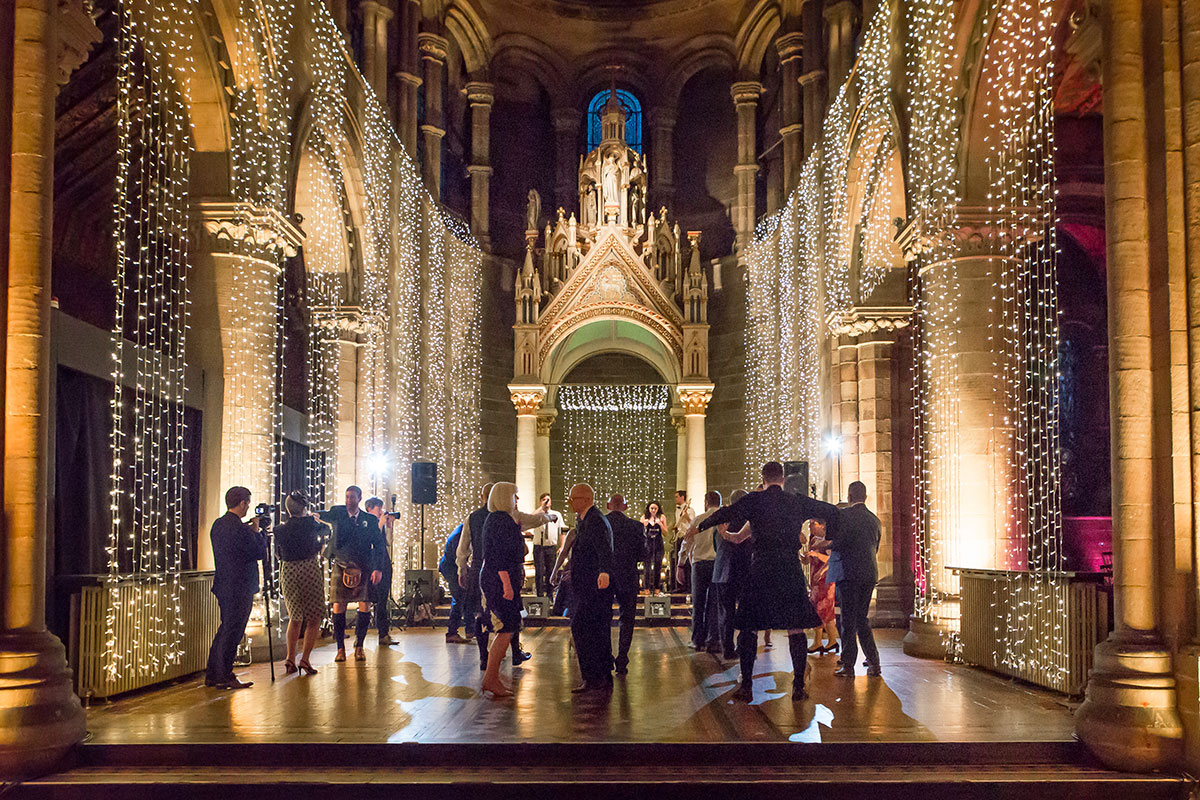 Evening reception at Mansfield Traquair with guests dancing beneath illuminated arches and golden fairy lights.