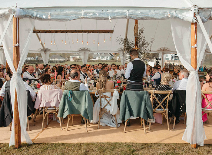 wedding guests seated in an open-sided marquee for dinner