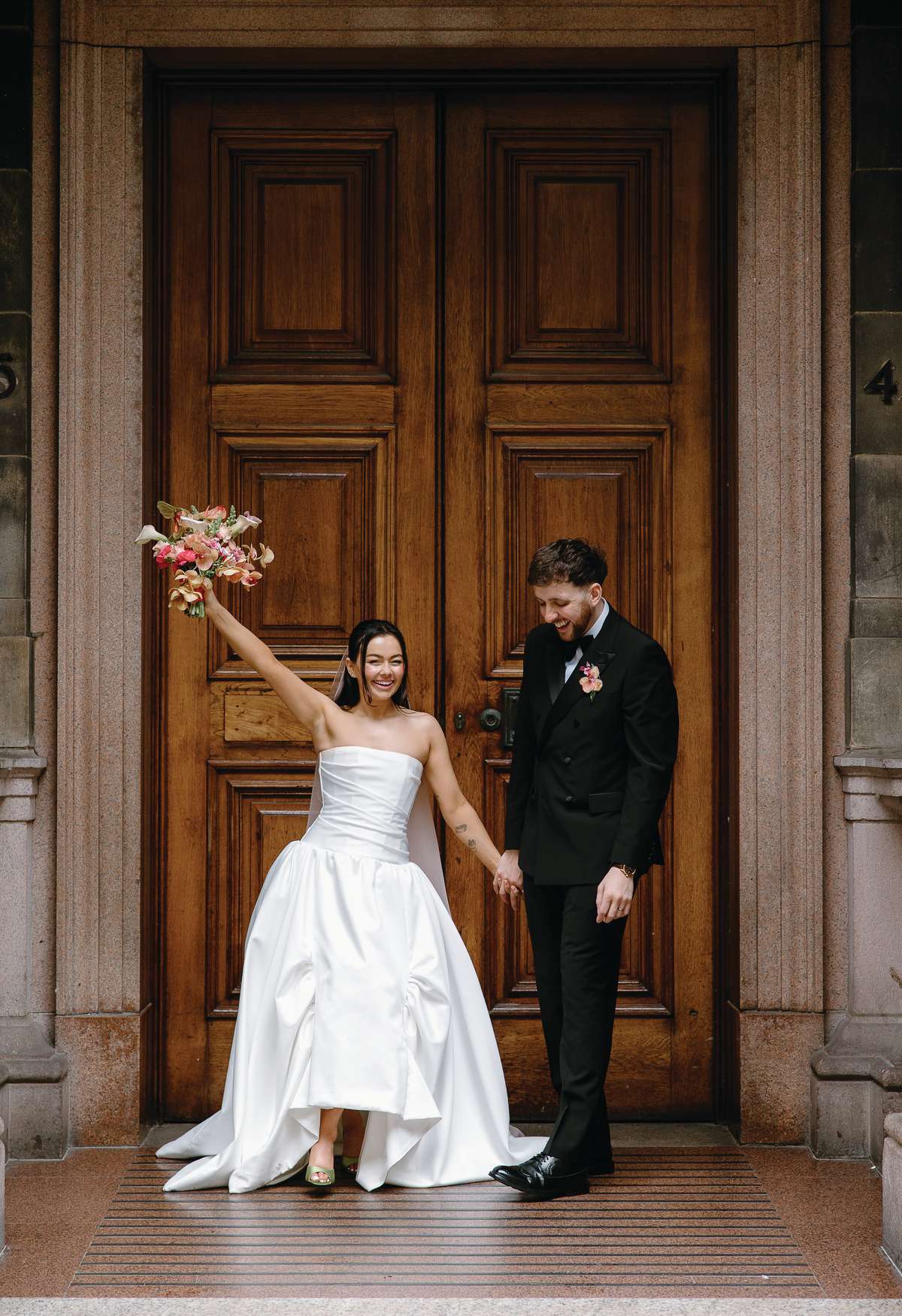 Newlyweds celebrate outside The Collector’s Hall Glasgow, with the bride holding up her colourful wedding bouquet.