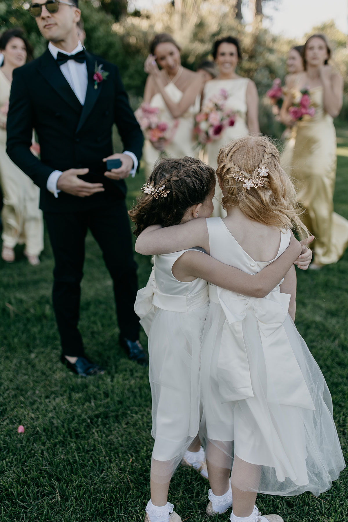 Flower girls hugging after the ceremony as the bridal party smiles at Boschendal Wine Estate wedding in South Africa