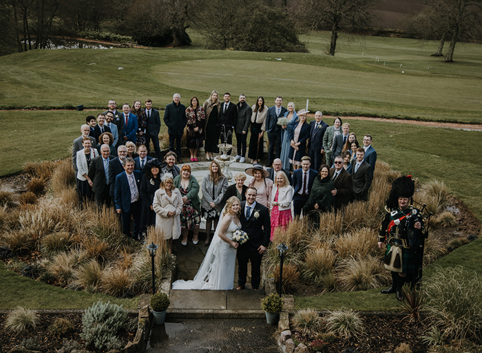 A group of people stand in a circle looking at the camera in a large garden