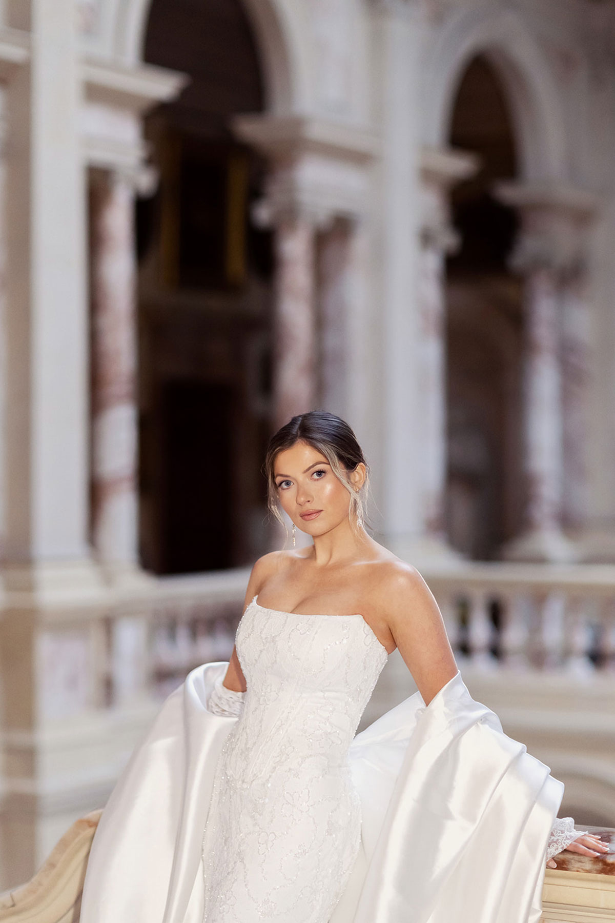 Bridal model in a strapless wedding dress with a satin wrap against the grand hall at Gosford House.