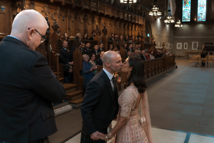 A Bride And Groom Kissing At A Wedding Ceremony At Glasgow University Memorial Chapel