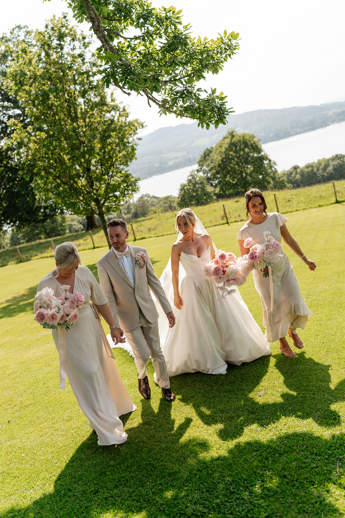 Bride, bridesmaids and groom walk through the grounds of Boturich Castle overlooking Loch Lomond before the wedding ceremony.