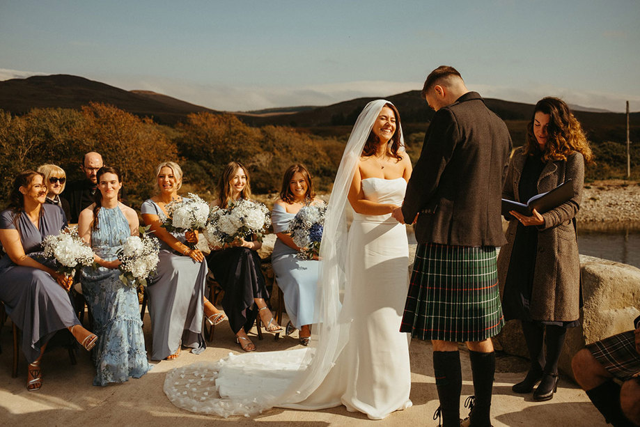 outdoor ceremony at dougarie boathouse as bride and groom say marriage vows as guests watch