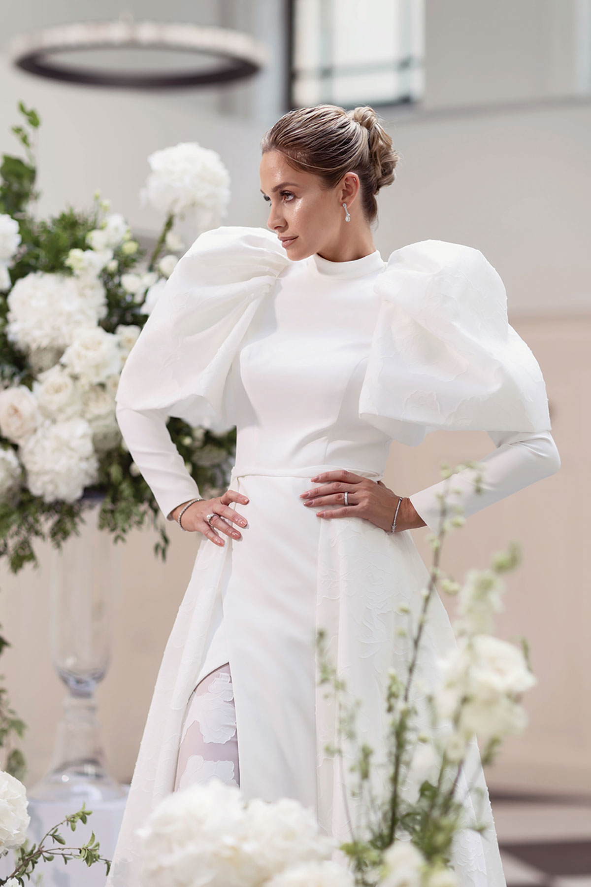 Close-up of bride in puff sleeve wedding dress with sleek updo and diamond earrings