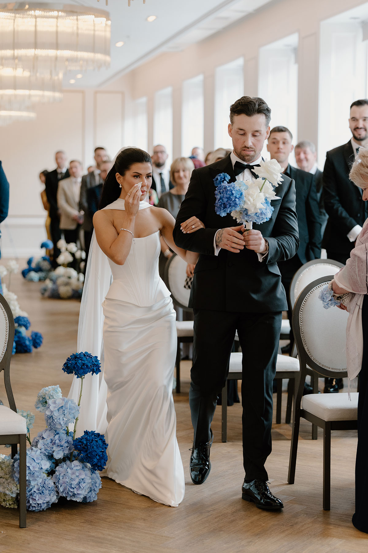 Emotional bride walking down the aisle arm in arm with the groom during their wedding ceremony at The Exchange in Glasgow.