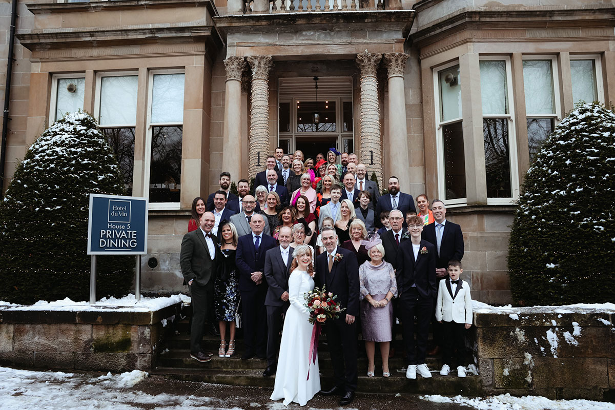 a group of wedding guests standing in front of a grand building on the front stairs