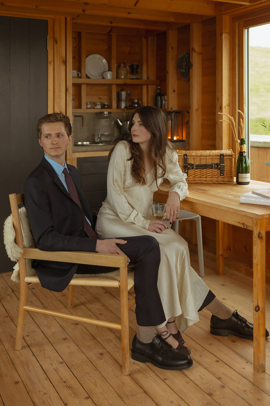 bride sits on grooms knee holding glass of white wine at guardswell farm