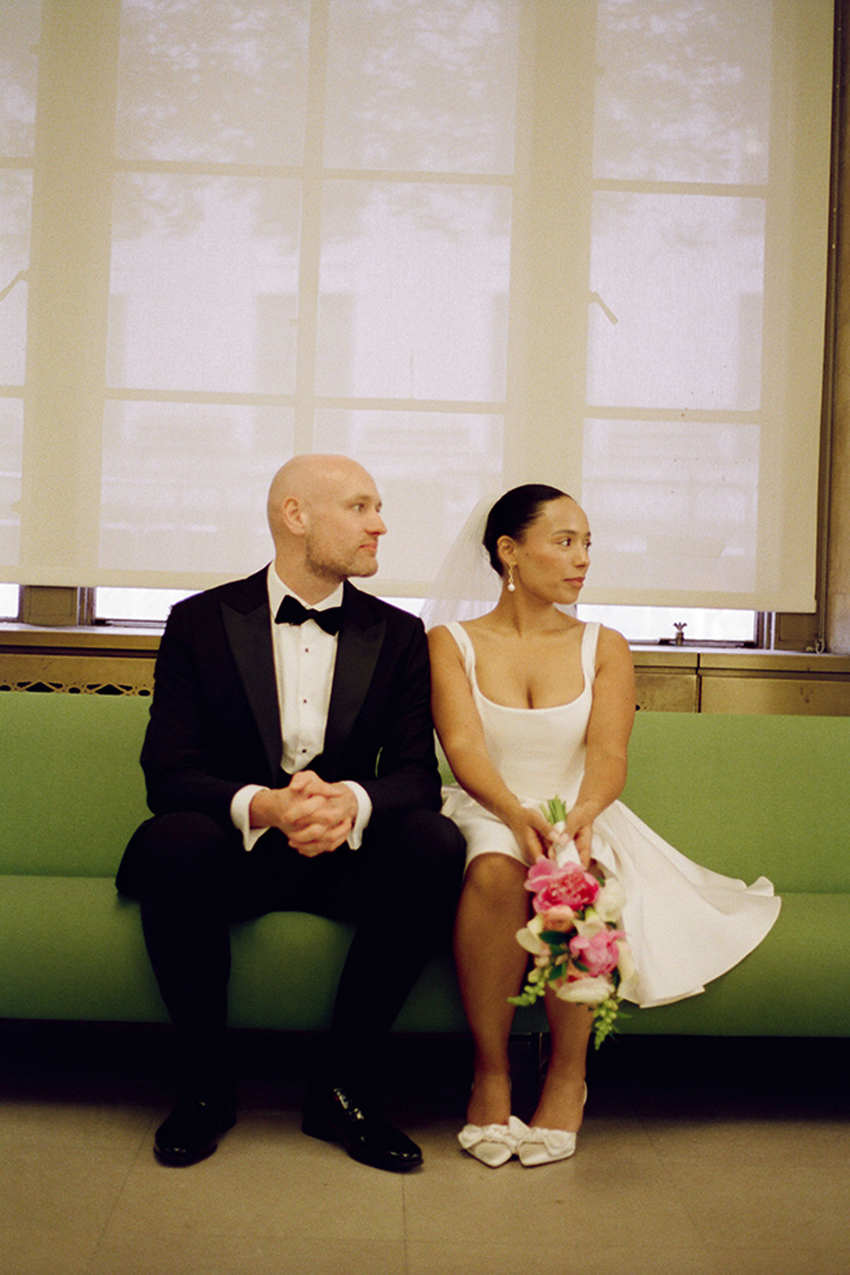 Bride and groom seated on bench waiting inside New York City Hall before wedding ceremony