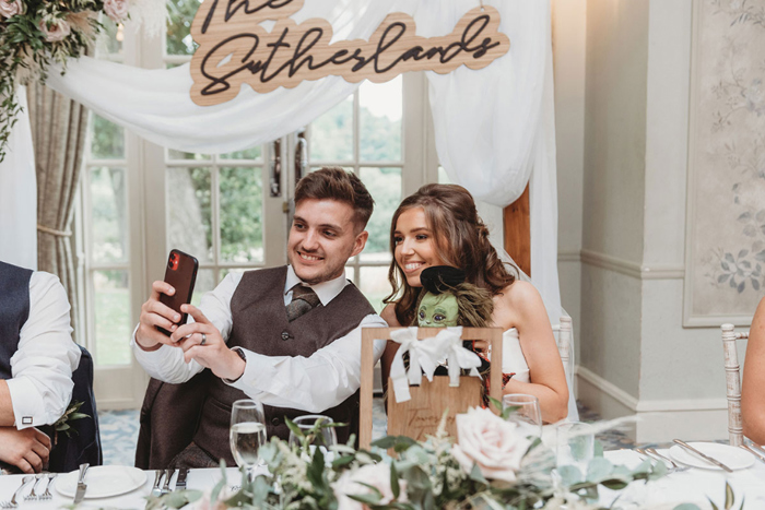 Bride and groom take selfie with toy at the top table