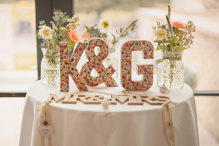 Wooden letters with the initials 'K & G' in a floral print and the words 'Mr & Mrs' on a table 
