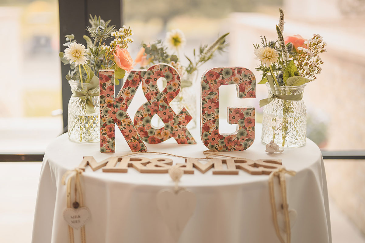 Wooden letters with the initials 'K & G' in a floral print and the words 'Mr & Mrs' on a table