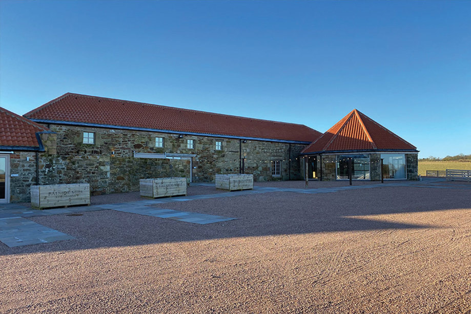 The exterior of a one storey stone building with a red roof 