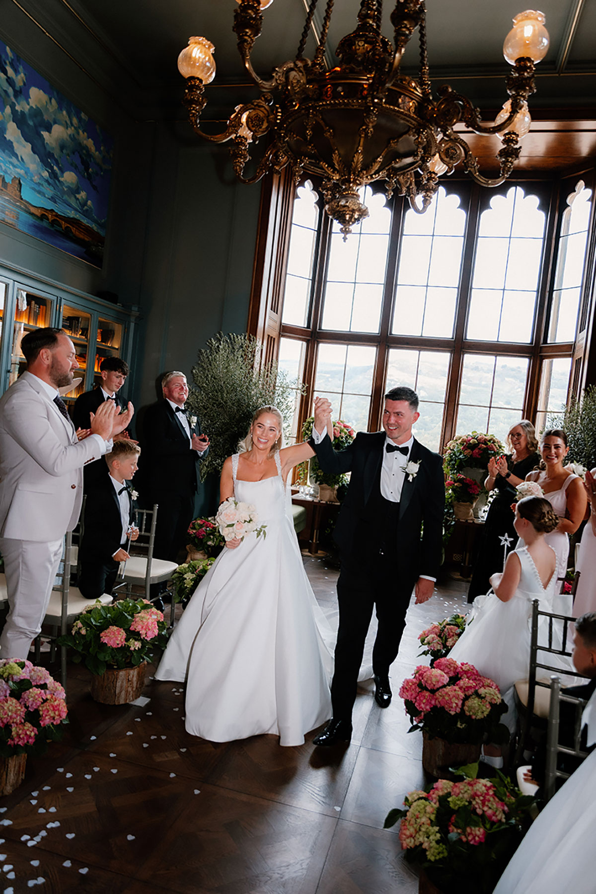 Bride and groom walking back up the aisle at Mar Hall to cheers and applause from guests.