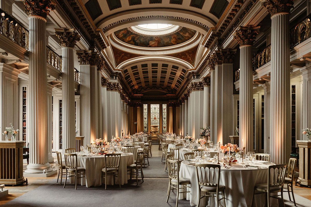 Upper Library at The Signet Library in Edinburgh set for a wedding reception with round tables beneath ornate columns and painted ceilings.