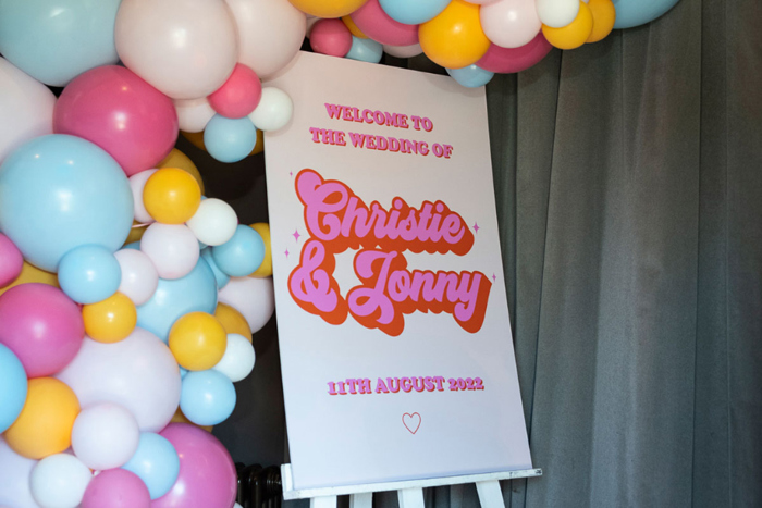 Pink and orange colourful wedding welcome sign with balloons