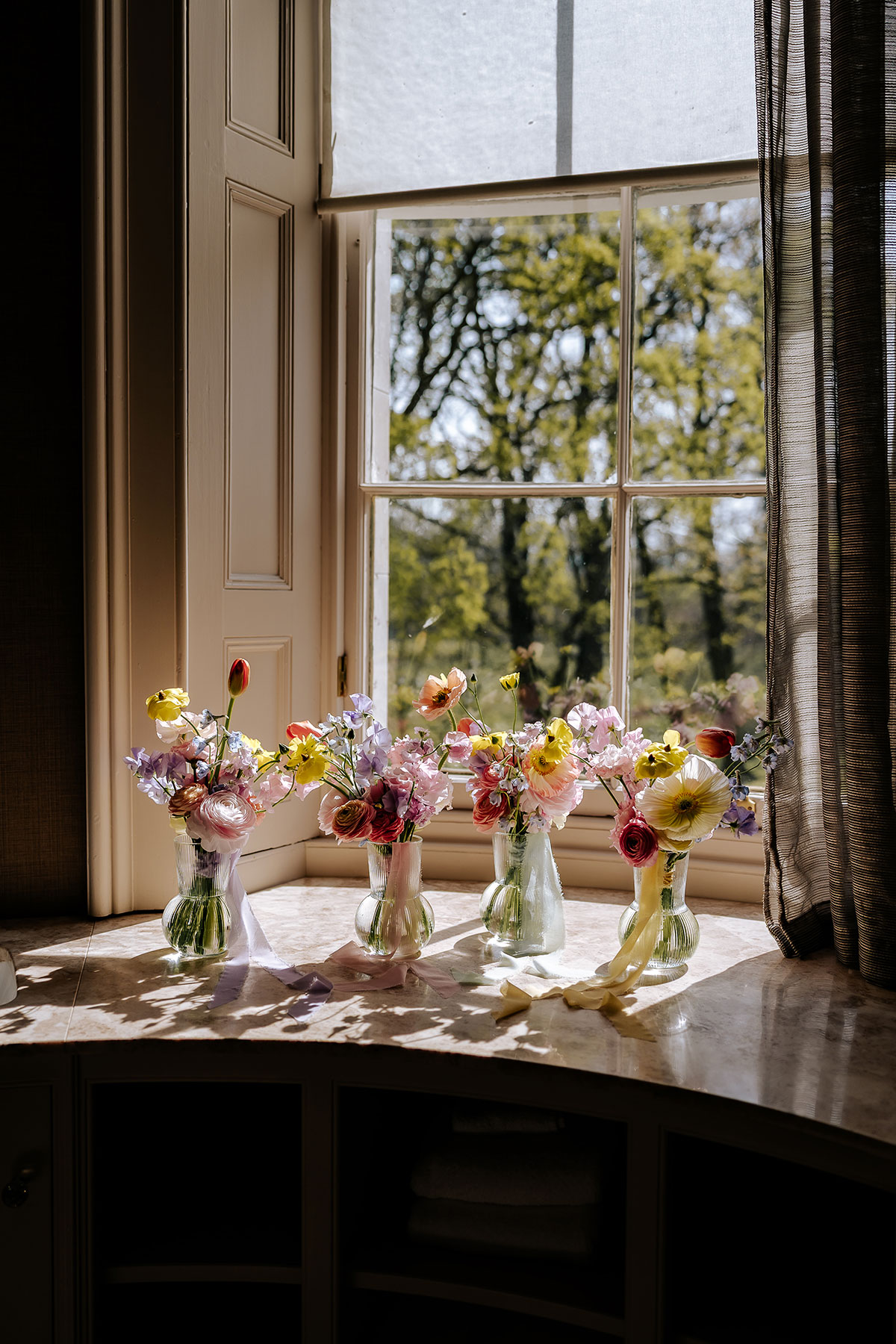 wedding flowers in vases in a window at Carlowrie Castle