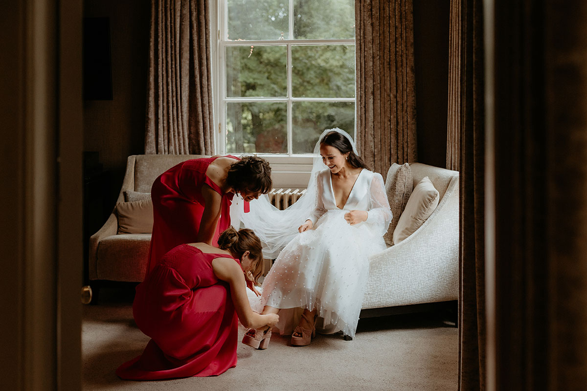 a bride with bridesmaids in a bedroom at Carlowrie Castle